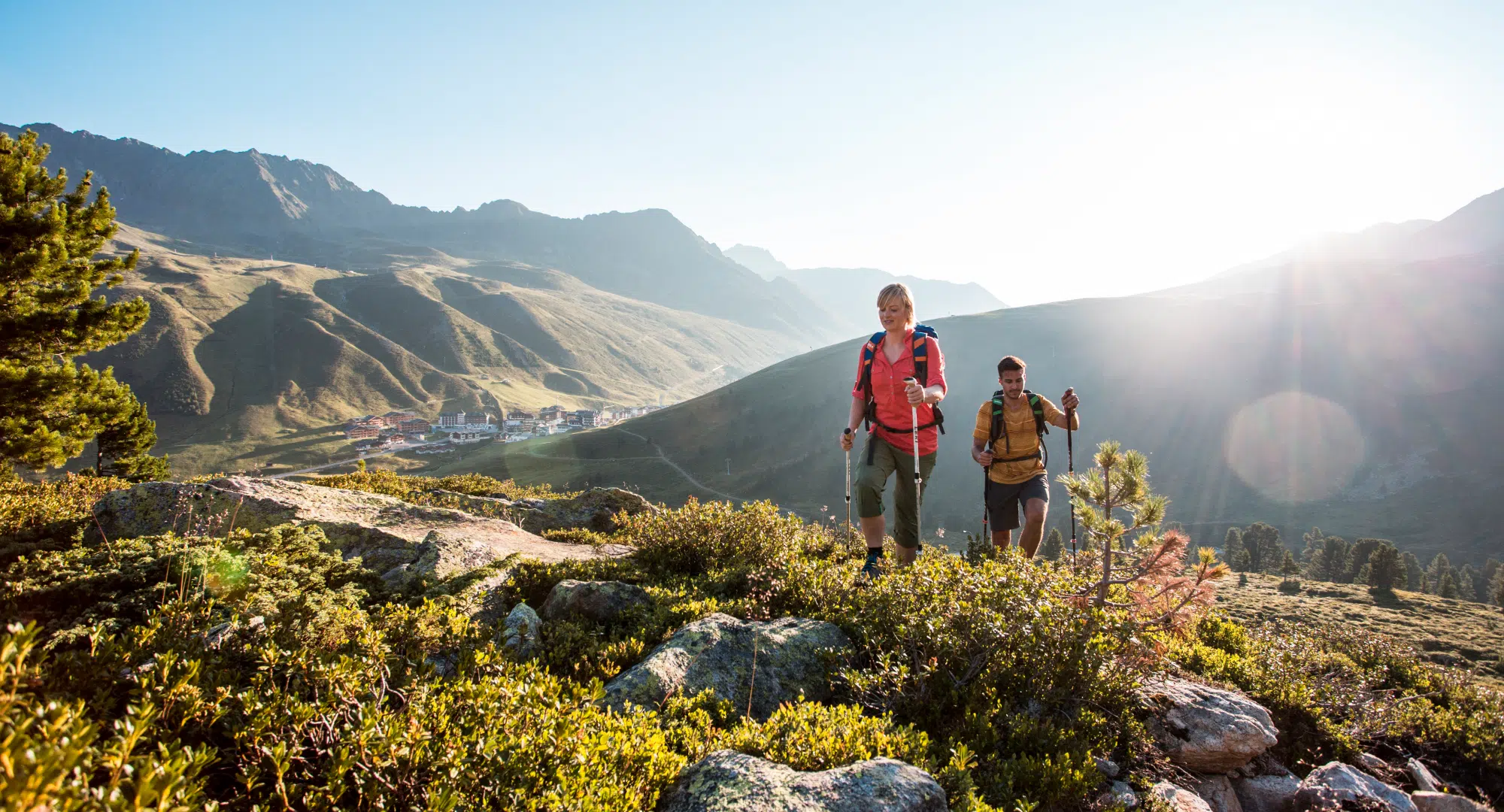 Zwei Personen wandern auf einem felsigen Bergpfad in der Nähe malerischer Hügel – perfekt für Liebhaber des Appartments Sellrain.
