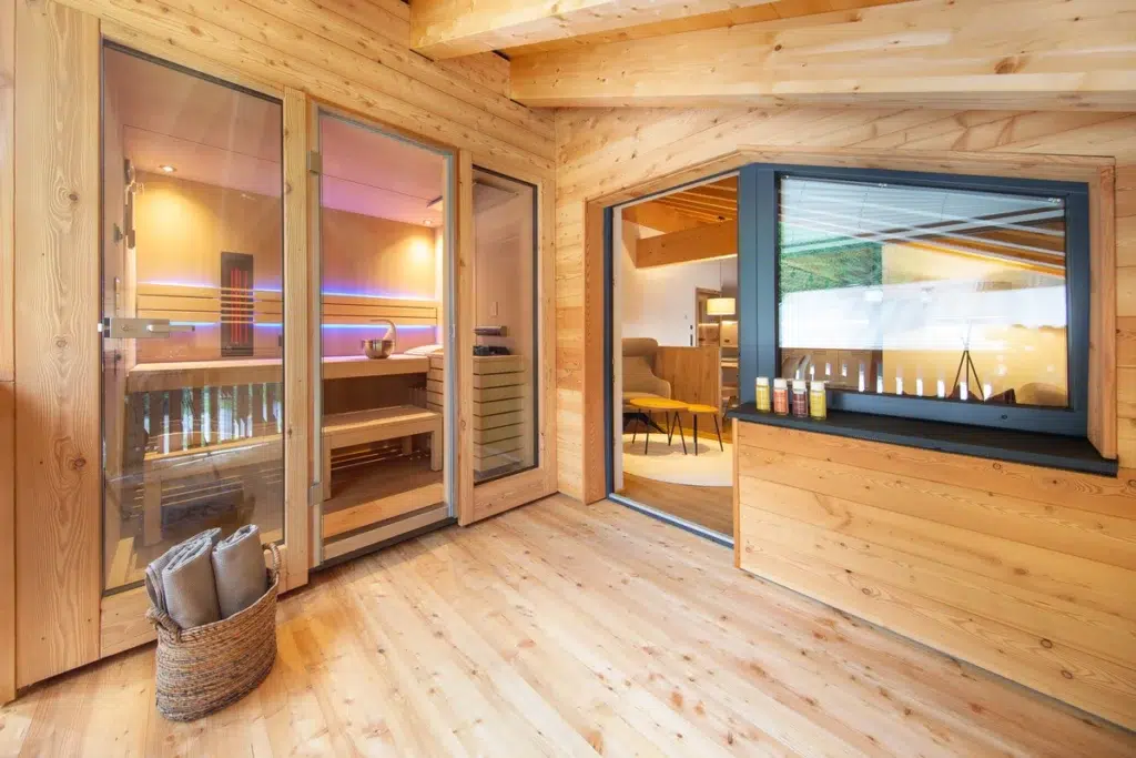 Moderne Holzsauna in den Appartements Sellraintal, mit großen Fenstern und einer gemütlichen Sitzecke.
