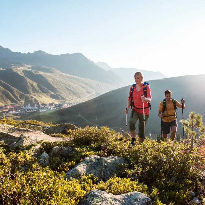 Zwei Personen wandern auf einem felsigen Bergpfad in der Nähe malerischer Hügel – perfekt für Liebhaber des Appartments Sellrain.